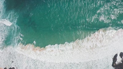 在黄金时刻飞过海洋。巨大的波浪在海洋中激起泡沫和水花。冲浪者乘风破浪。夏威夷瓦胡岛上的太平洋海水的蓝