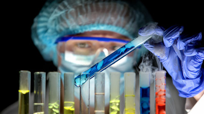 科学家拿着装有蓝色液体的试管分析反应，实验室研究