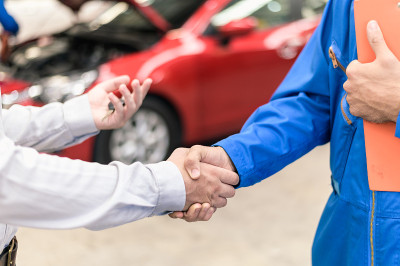 汽车服务、汽车维修理念:汽车服务技术人员将汽车送到汽车服务中心维修或检查后，与车主客户握手。