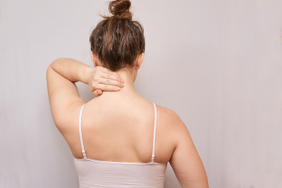 Girl hold hand near neck. Back view