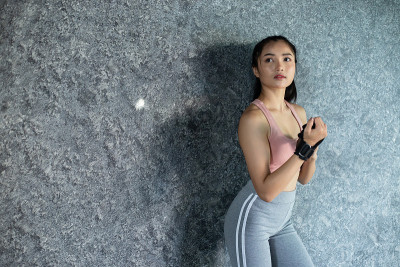 妇女戴腕带锻炼，靠墙站着。