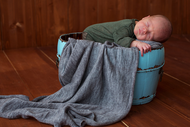 smiling newborn baby lies in a round bowl, in a wo