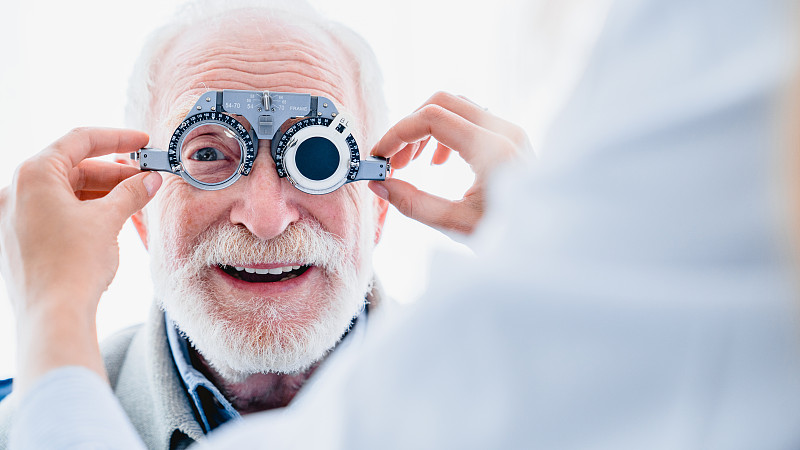 Smiling elderly man checking up vision with specia