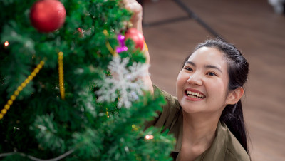 年轻的亚洲妇女很乐意在家里装饰圣诞树