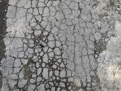 背景纹理地块的老城道路被汽车车轮粉碎成集小块灰色与黑色轮廓的湿土