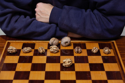 核桃躺在棋盘上。棋手的手后面