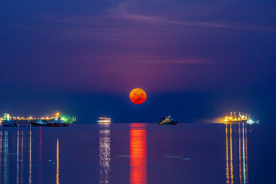 超级血月在sracha港与船只货物集装箱船在海面上。夜景拍摄