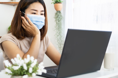 亚洲商务女性在家办公，戴着防护面具