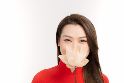 一个美丽的女孩穿着越南服装，拿着一朵幸福的荷花。