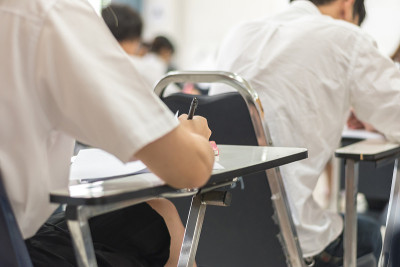 模糊学校背景的大学生在教室里写答案做考试