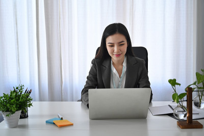 自信的女商人工作与笔记本电脑在她舒适的工作场所。