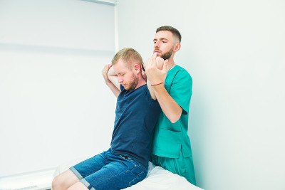 男患者接受治疗师按摩。在医务室里，脊椎按摩师在为病人伸展脊柱和双手。神经系统体格检查。整骨疗法、按摩