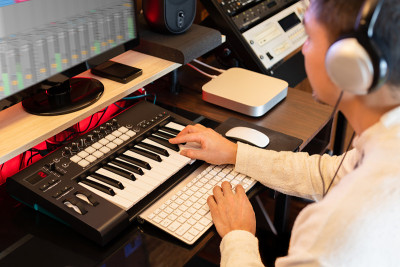 亚洲人在家庭工作室学习电脑上的在线音乐制作技术和MIDI键盘