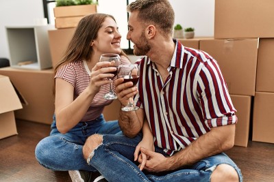 年轻的白种人夫妇微笑着在新家喝着红酒快乐干杯