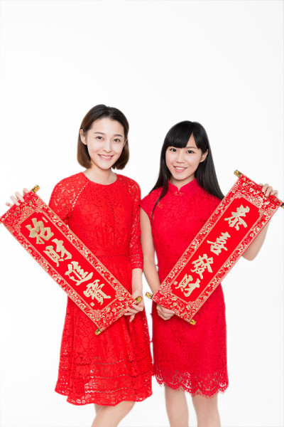 两个年轻的女人拿着中国对联，微笑着对着镜头