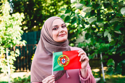 Muslim woman in a scarf holds flag of Portugal