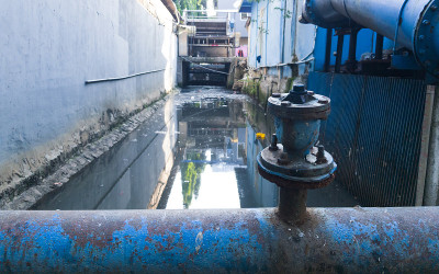 自来水的金属管道穿过雅加达那条被污染的河流