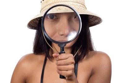 戴着旅行帽的女孩用放大镜看东西