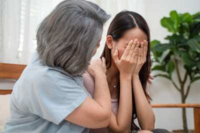 亚洲慈爱的老年母亲安慰和安慰沮丧沮丧的年轻女孩的女儿哭泣的问题。关心老妈妈的支持和理解，同情在家里流