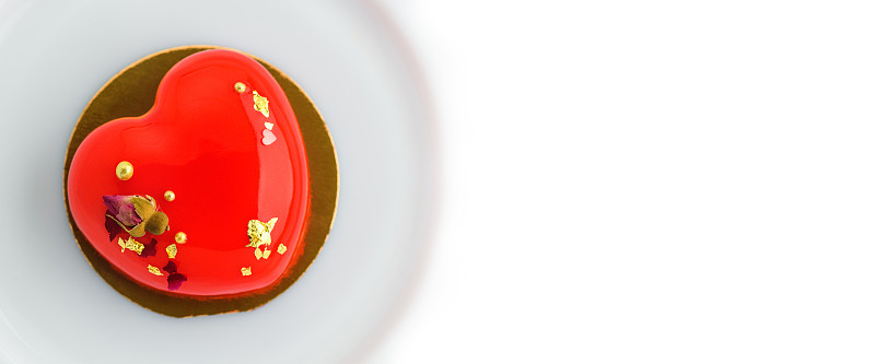 心形的蛋糕。一个心形的慕斯纸杯蛋糕放在盘子上，背景是白色的。情人节的旗帜面包店，糖果。本空间