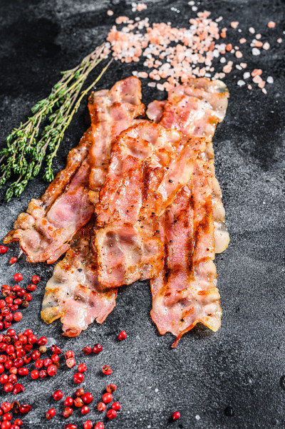 煮熟的，炙热可口酥脆的培根。黑色背景。俯视图