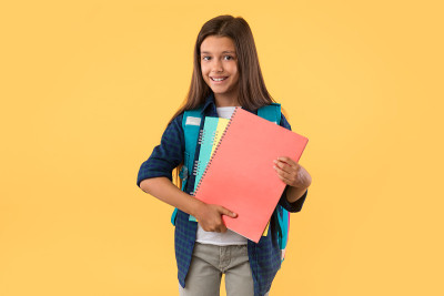 Smiling girl holding textbooks at orange studio ba