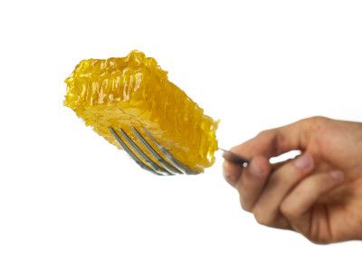 用手拿着叉子上的蜂巢，白色背景，超级营养的食物