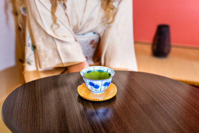 传统的日本妇女在仪式中穿着和服坐在壁龛旁挂纸卷轴喝绿茶