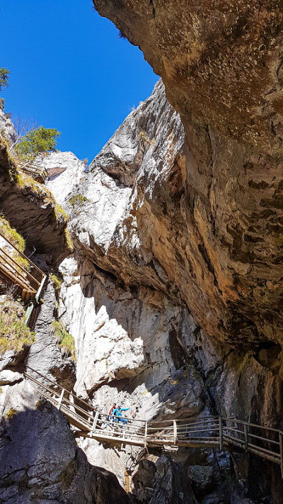Baerenschuetzklamm -一对夫妇在奥地利阿尔卑斯高山峡谷的木制梯子上散步。有一个瀑布