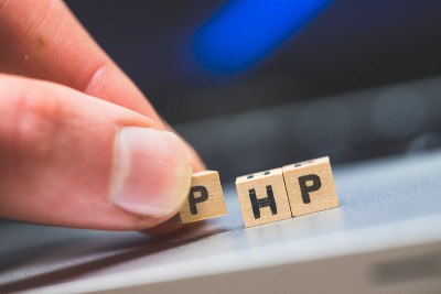 PHP编程网络语言:字母“PHP”的木制立方体躺在笔记本电脑上，概念