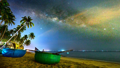 午夜景观与篮子船，椰子树剪影和银河在天空