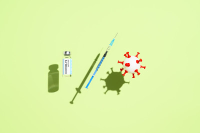 冠状病毒疫苗接种的概念。小瓶疫苗，医用注射器，和悬浮在淡绿色背景上的白色病毒球。俯视图