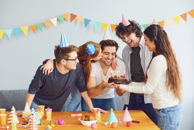 快乐的生日聚会。一群朋友拿着蛋糕祝他生日快乐