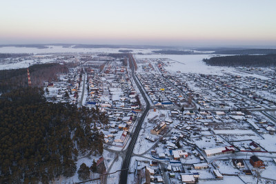 鸟瞰图的Oktyabrski村庄与道路，森林和雪原。俄罗斯。冬天,傍晚,日落