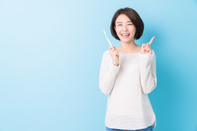 漂亮的亚洲女人用健康的牙齿拿着牙刷，口腔护理