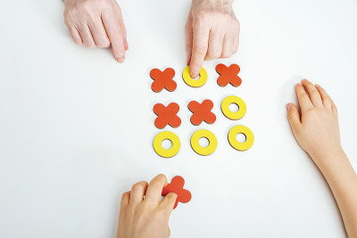 手奶奶和孙子玩一字棋木桌游戏。发展的游戏。家庭关系、传统和消遣的概念。XO XO符号。