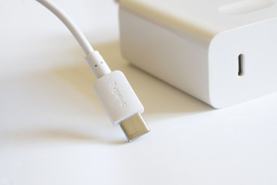 一个白色usb type-c连接器和一根电线放在一个白色电源和快速充电器旁边的灯光背景上。现代技术和