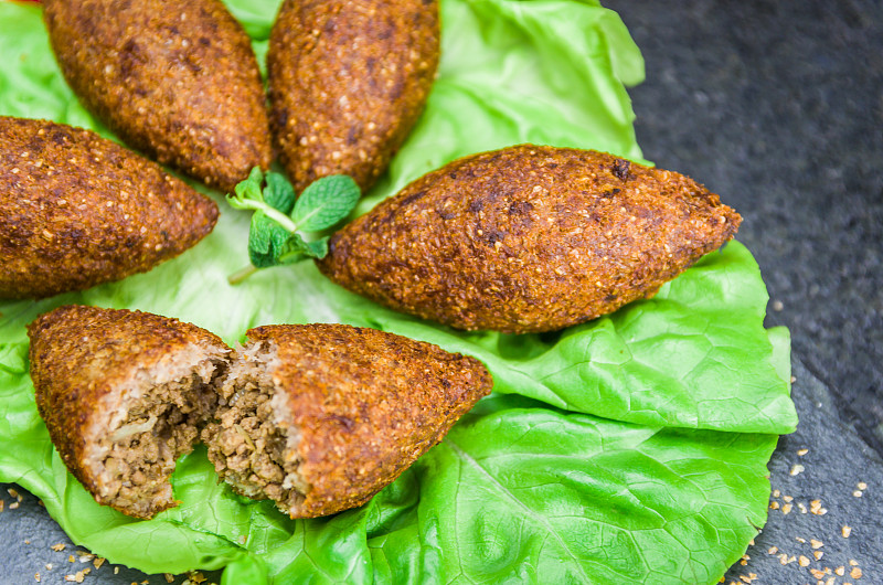 美味的黎巴嫩(阿拉伯)食物，kibbeh (kibe)酱汁和柠檬在黑色石板石和花岗岩背景与传统的ke