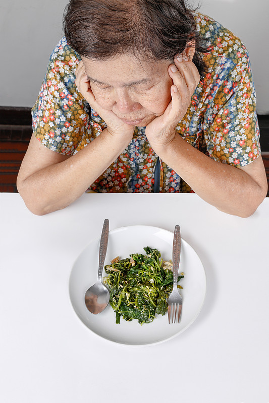 年老的亚洲妇女厌倦了食物