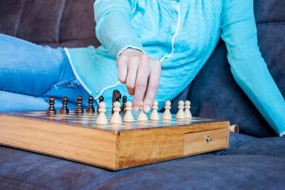 一个女人的手握着棋盘上方的棋子
