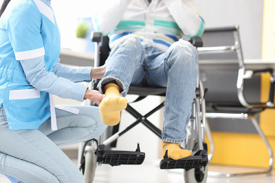 康复医生帮助抬轮椅病人的腿特写