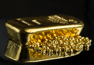 金条和一堆纯金颗粒在镜子般的暗色背景上