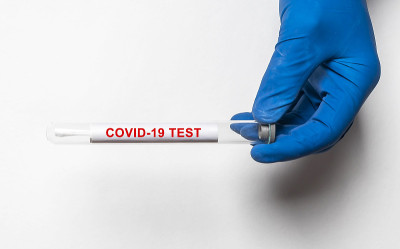 COVID-19测试铭文。冠状病毒概念放在试管桌上，医生双手戴手套，俯视图
