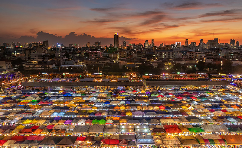 泰国铁路夜市上的亚洲街头美食俯视图，夜间有五颜六色的摊位和灯光