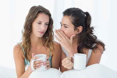 女性朋友拿着咖啡杯在床上闲聊