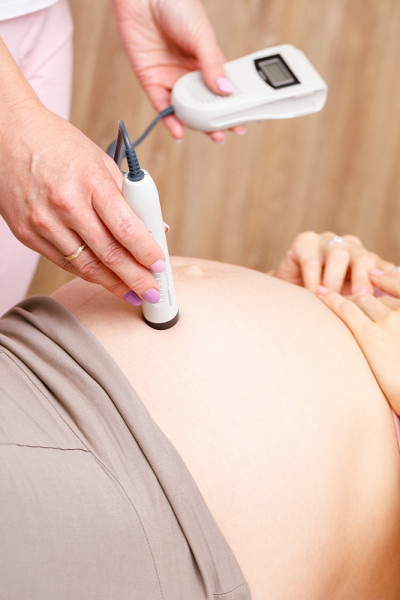 妇科医生在产前检查中使用多普勒胎儿监视器检查胎盘和子宫的血流
