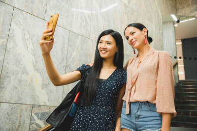 快乐的中国亚洲女友在户外玩手机