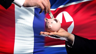 法国投资朝鲜手把钱放在小猪存钱罐的背景旗上