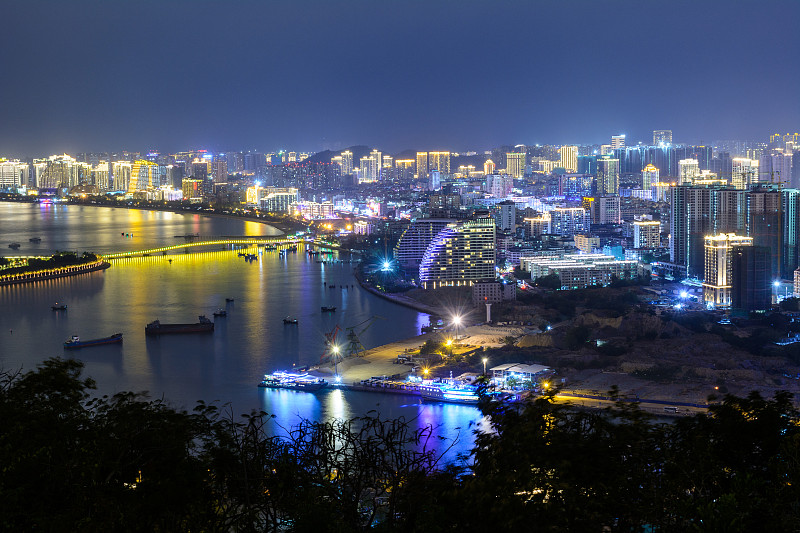 夜景三亚市与明亮的彩色照明建筑，结构，道路，人行道，杆子，桥梁。