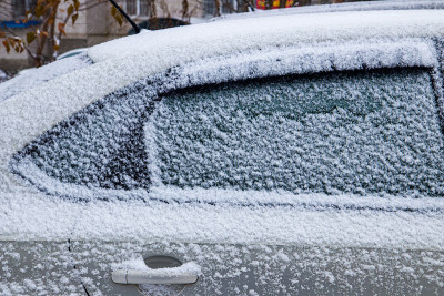 汽车上覆盖着厚厚的一层雪。大雪的负面后果。侧百辆不同图案的汽车。